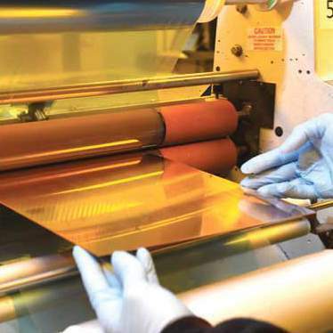 A worker extracts a sheet of copper from an etching machine